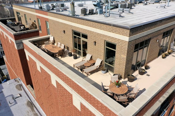 Rooftop with seating area and air conditioning units.