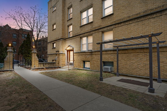 Front view of a multi-story brick building with a pathway leading to the entrance.