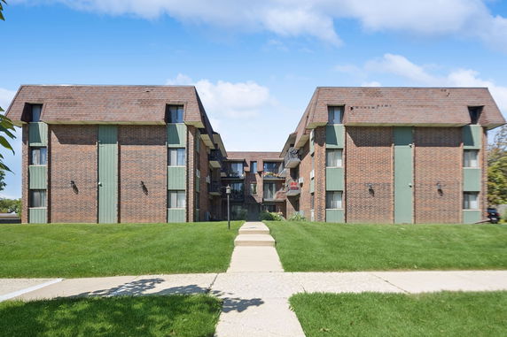 Front view of a multi-story brick building complex with green panels.