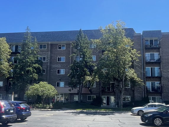 Front view of a multi-story brick residential building with balconies.