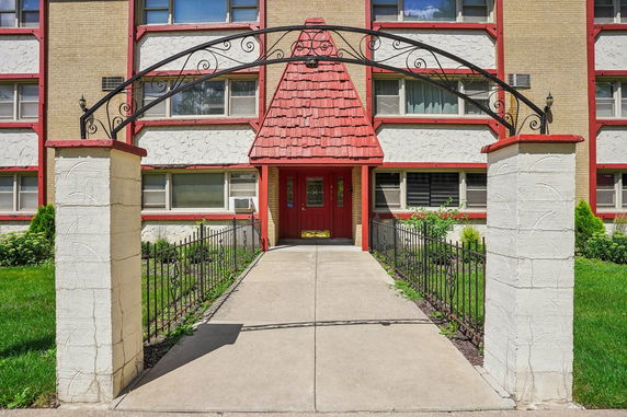 Front view of a multi-story building with a red entrance and decorative archway.
