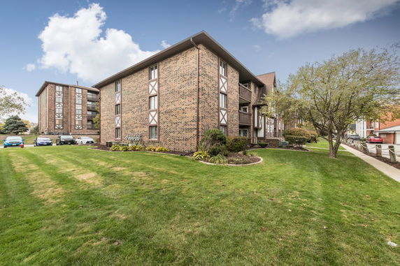 Front view of a multi-story brick building with a landscaped lawn.
