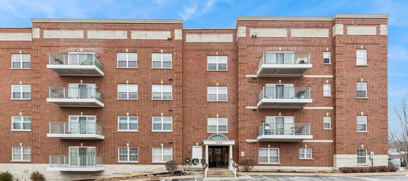 Front view of a multi-story brick apartment building with balconies.