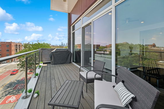 Balcony view with outdoor seating and glass railing overlooking the street.
