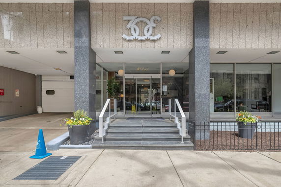 Front view of a building entrance with stairs and glass doors.