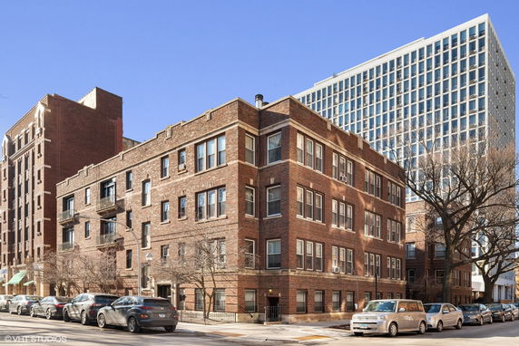 Exterior view of a brick apartment building on a city street corner.