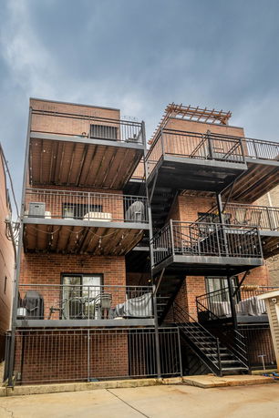 Rear view of a multi-story brick building with metal balconies and staircases.