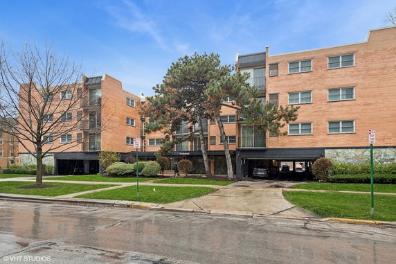 Front view of a multi-story brick apartment building with balconies.