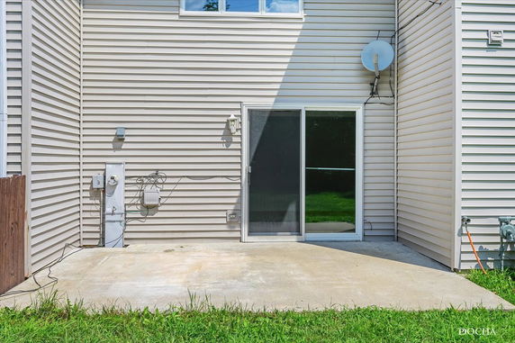Rear view of a house with sliding glass door and satellite dish.