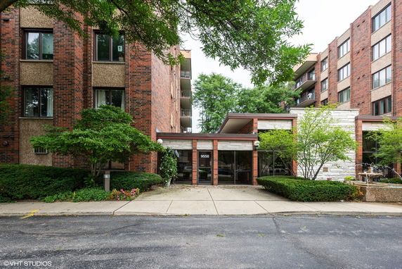 Front view of a multi-story brick apartment building with a central entrance.