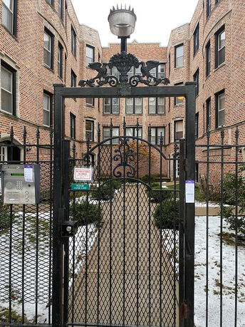 Front view of a brick apartment building with a decorative iron gate.