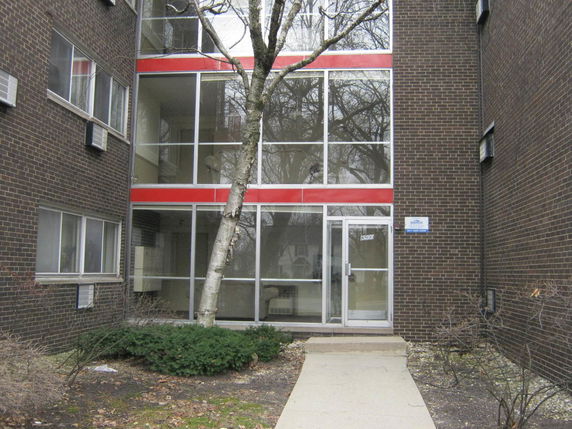Front view of a multi-story building entrance with glass doors and windows.