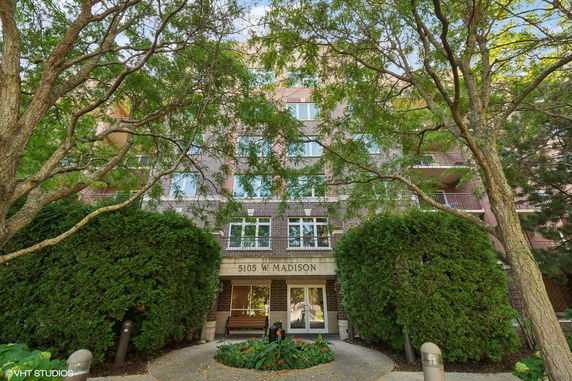 Front view of a multi-story brick building with a prominent entrance and balconies.
