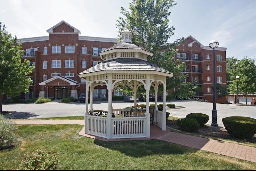 Front view of a multi-story brick apartment building with a white gazebo in the foreground.