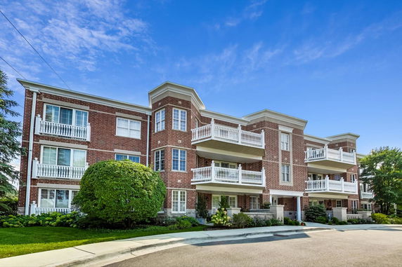 Front view of a multi-story brick apartment building with balconies.