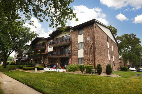 Front view of a multi-story brick apartment building with balconies.