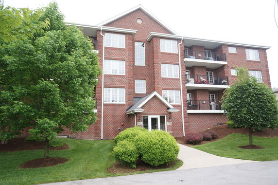 Front view of a multi-story brick apartment building with balconies.