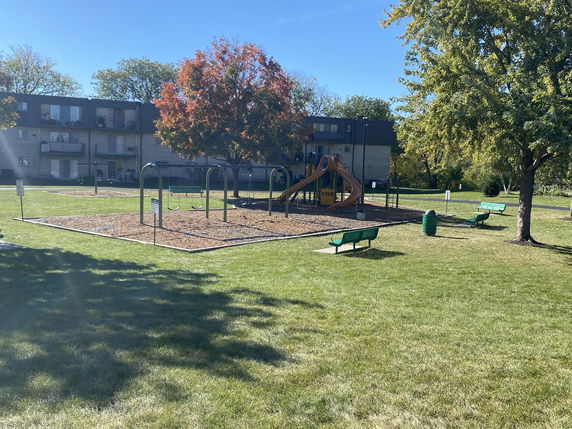 Playground area with swings and slides, surrounded by grassy field.