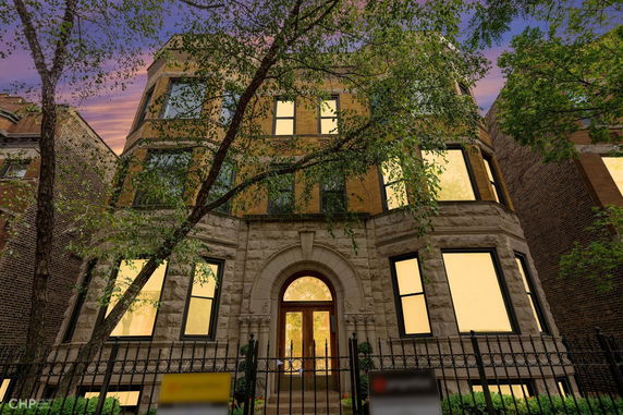 Front view of a multi-story building with an arched entrance and numerous windows.
