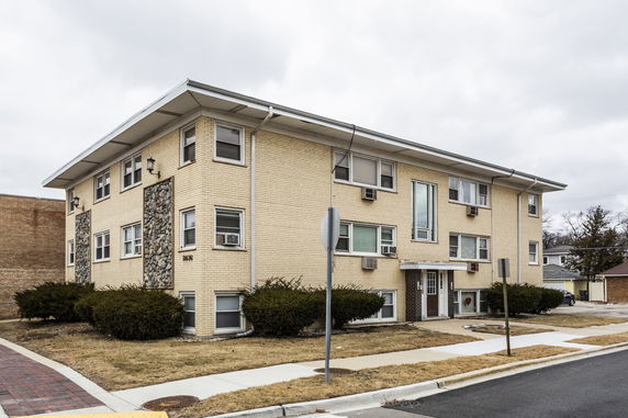 Front view of a multi-story residential building with brick exterior and stone accents.