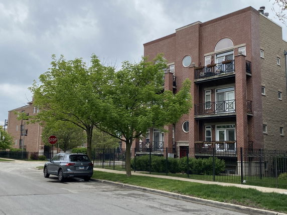 Front view of a multi-story brick apartment building with balconies.