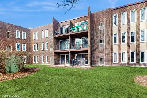 Front view of a multi-story brick apartment building with balconies.