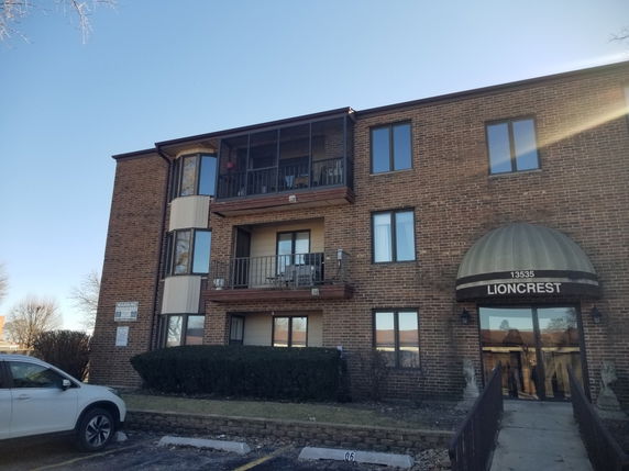Front view of a multi-story brick building with balconies and an entrance canopy.