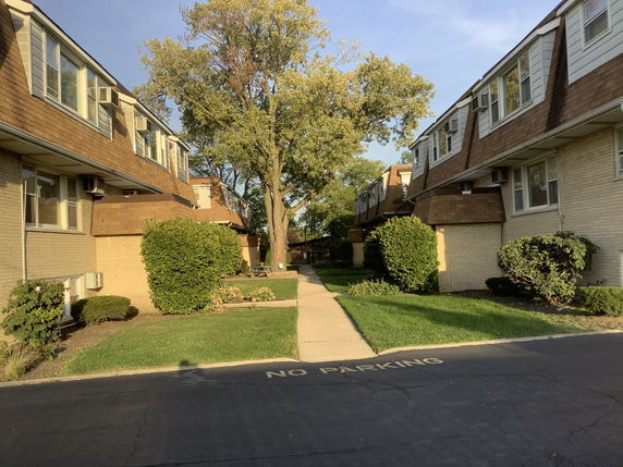 Front view of two-story apartment buildings with brown roofs and light brick exterior.