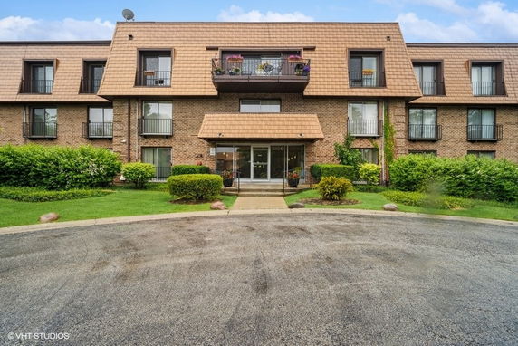 Front view of a multi-story residential building with balconies and a central entrance.