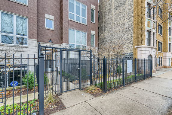 Front view of a multi-story brick building with gated entry.