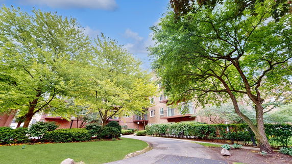 Front view of a building surrounded by trees and greenery.