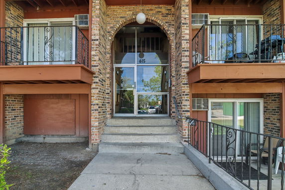 Front view of a brick apartment building entrance with balconies.
