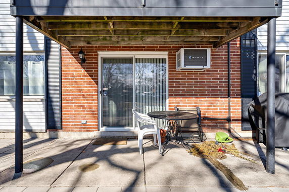Front view of a house with a small patio area and sliding glass door.