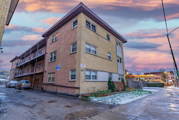 Front view of a multi-story apartment building with brick exterior and balconies.