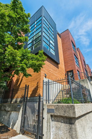Front view of a modern multi-story building with a black and red brick exterior.