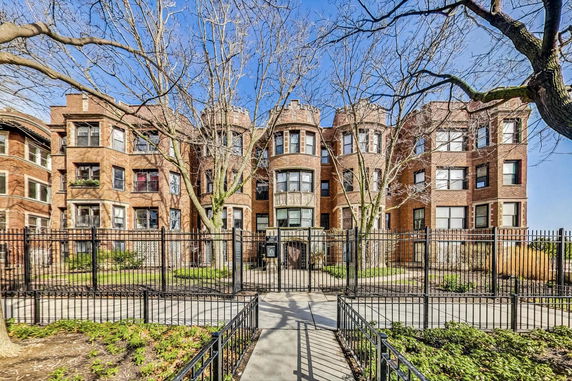 Front view of a multi-story brick apartment building with bay windows and decorative stonework.