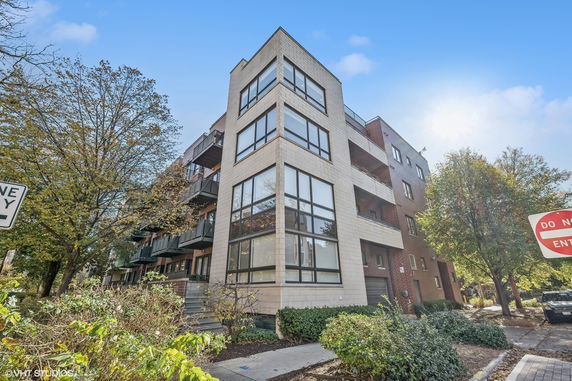 Front view of a multi-story apartment building with large windows.