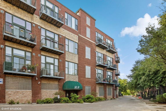 Front view of a multi-story brick apartment building with balconies.
