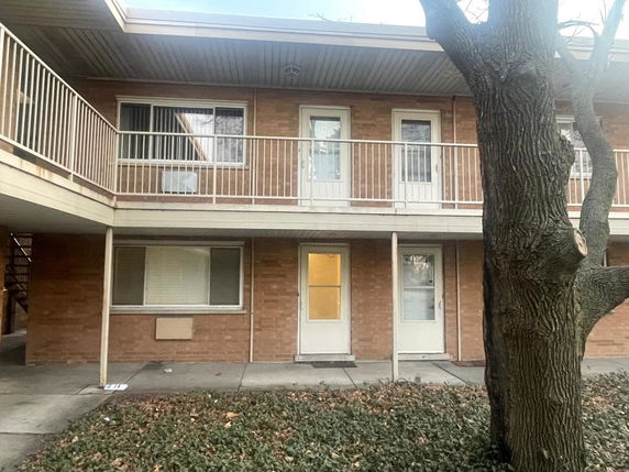 Front view of a two-story building with brick exterior and balcony.