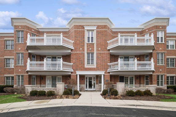 Front view of a multi-story brick building with balconies and white railings.