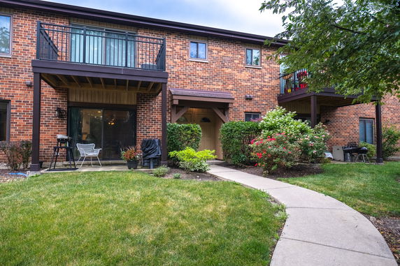 Front view of a two-story brick building with balconies and garden.