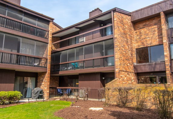 Front view of a multi-story brick apartment building with balconies.