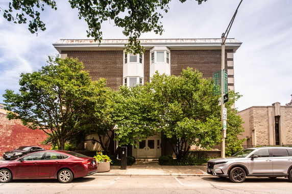 Front view of a three-story building with a brick exterior and bay windows.
