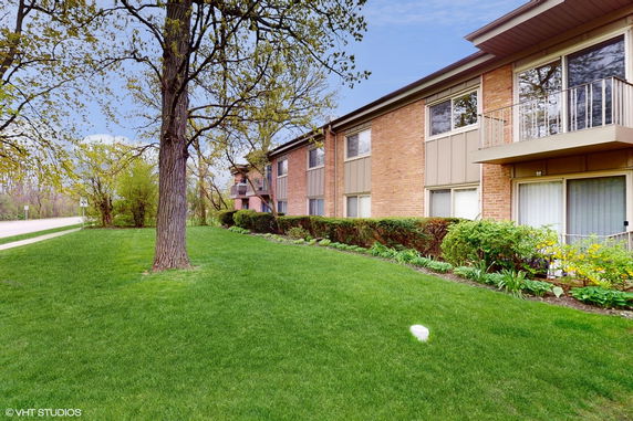 Side view of a two-story brick apartment building with balconies.