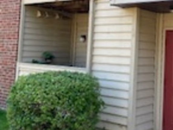 Front view of a house featuring wooden siding and a red door.