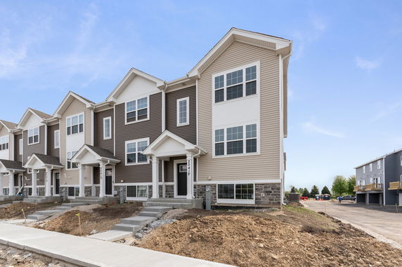 Front view of a modern multi-story townhouse with beige and brown siding.