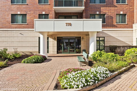 Front view of a multi-story building with a brick facade and a covered entrance.