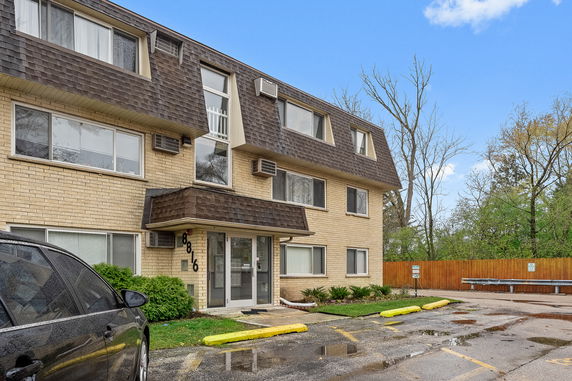 Front view of a three-story residential building with a sloped roof.