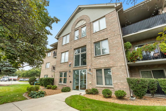 Front view of a multi-story brick apartment building with large windows and balconies.