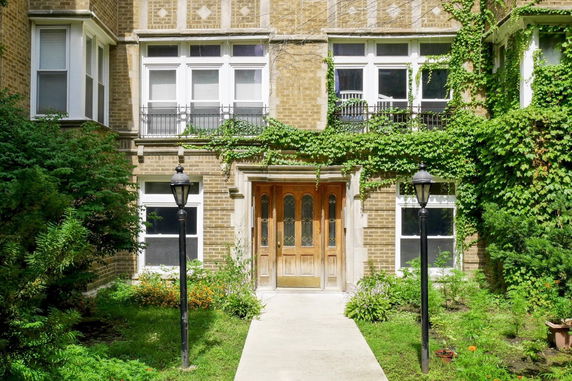 Front view of a multi-story house with ivy-covered walls and wooden door.